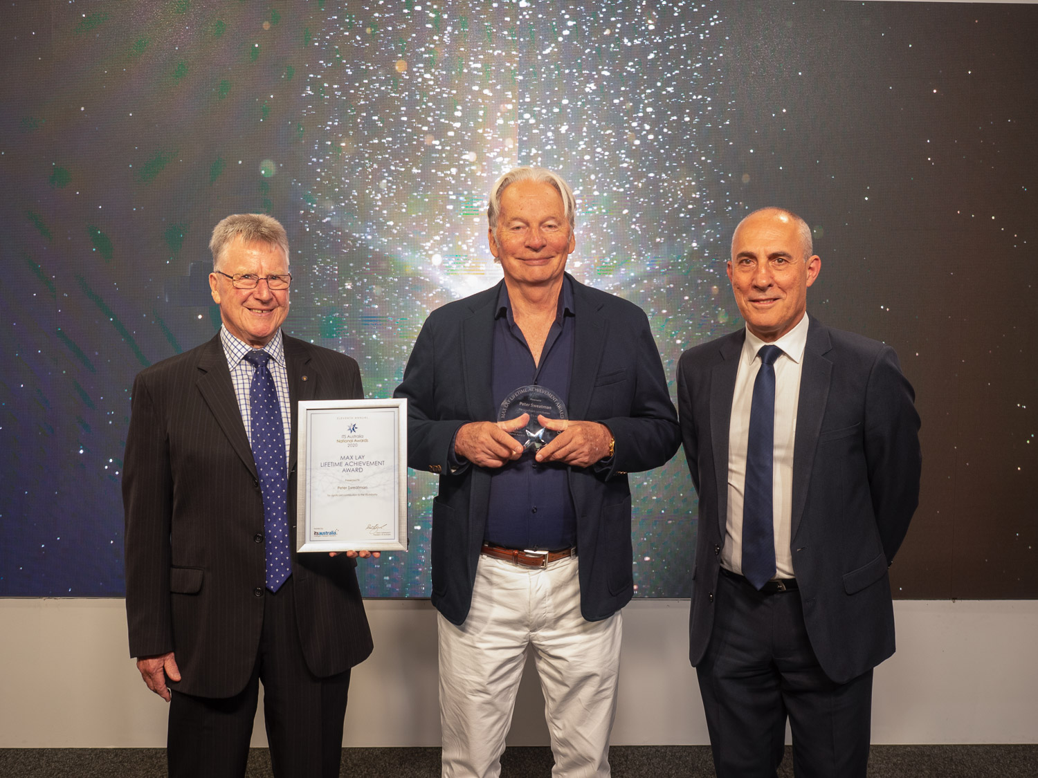 Brian Negus, ITS Australia ambassador and chairman, CICA Group (left) and Dean Zabrieszach, president, ITS Australia (right) present Dr Peter Sweatman (centre) with the 2020 Max Lay Lifetime Achievement Award (Credit: ITS Australia)